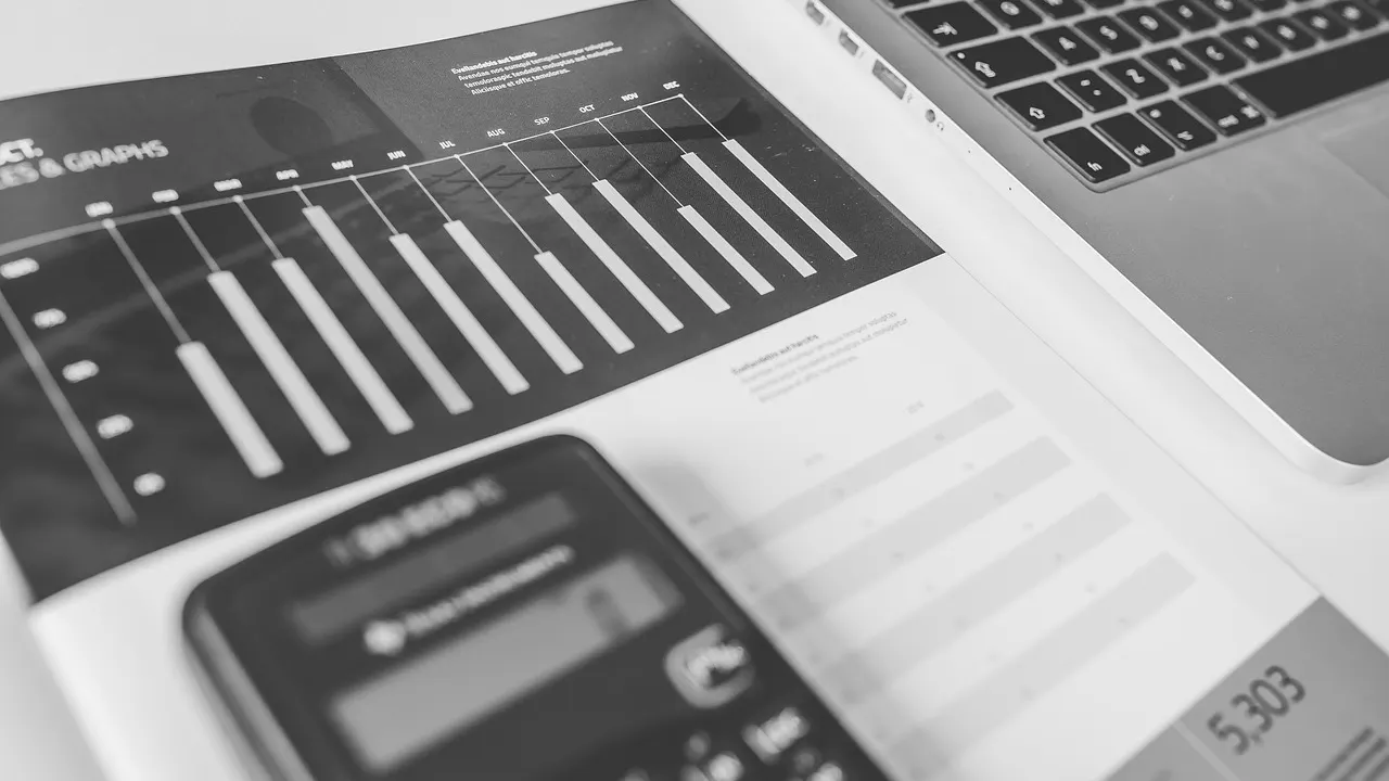 Calculadora junto a un portátil y documentos de contabilidad para planificar el coste de una automatización