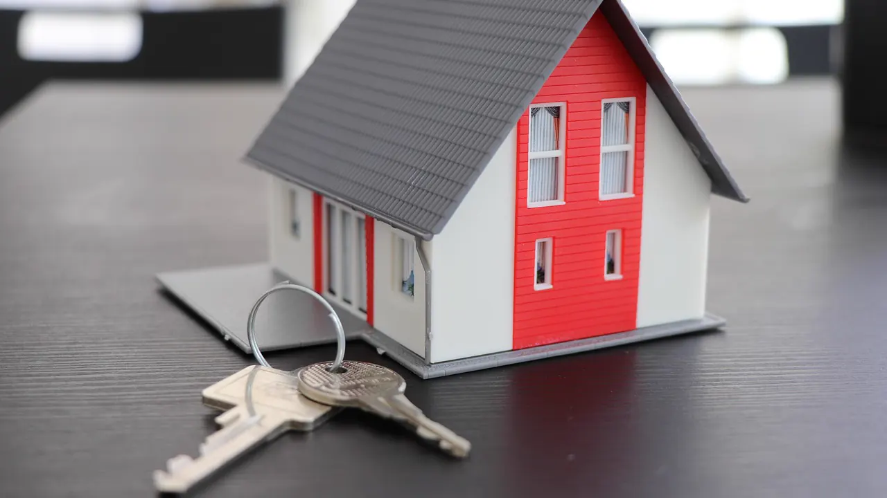 Maqueta de una casa junto a unas llaves para ilustrar una web profesional para inmobiliarias